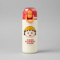 A Chibi Maruko water bottle with a cream-colored body, red and orange lid, and a printed cartoon character on a green grass background.